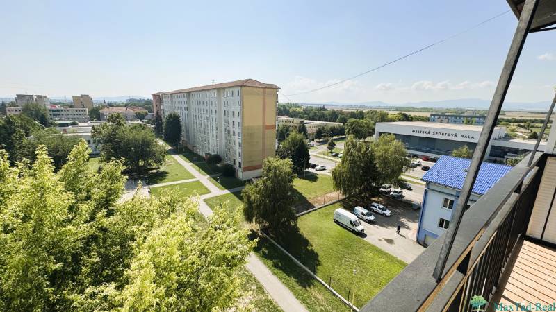 Výhľad z balkóna na zeleň, paneláky a Mestskú športovú halu v Trebišove.